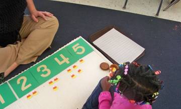 Montessori student playing a number-game with a teacher.